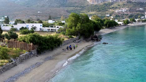 Eine-Gruppe-Von-Menschen,-Die-Yoga-Am-Malerischen-Strand-Ausüben,-4k,-Luftaufnahmen