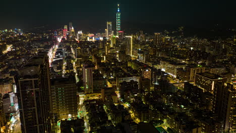 aerial hyperlapse shot of lighting cityscape at night with traffic on road and skyline in background - skyscraper buildings and tower illuminated at midnight