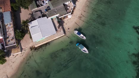 aerial top down view of coastal fishing village with vessel, pier, harbour and airport, caribbean island