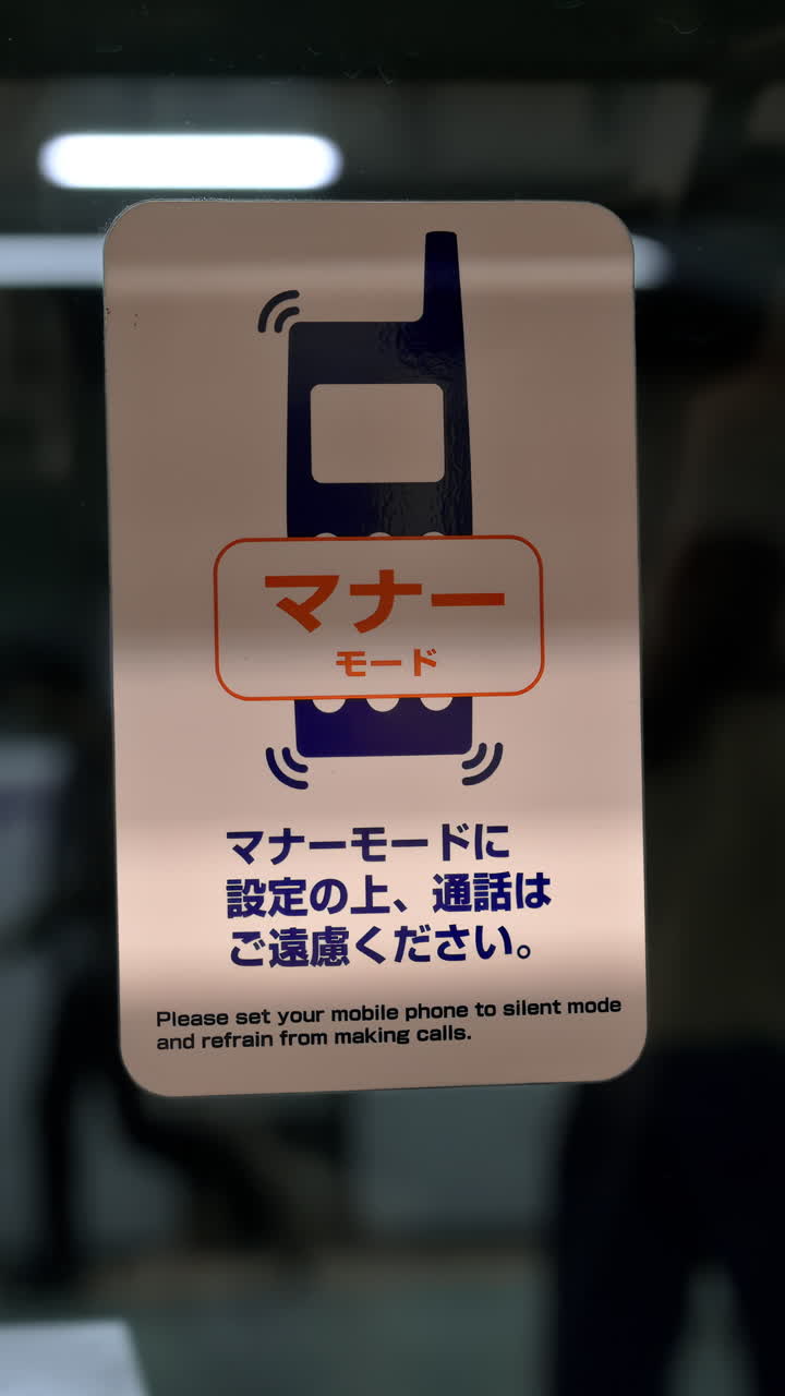 Tokyo, Japan - April 23, 2025: Close up of a sign prohibiting phone calls in subway with people walking on the background. Tokyo, Japan. Vertical