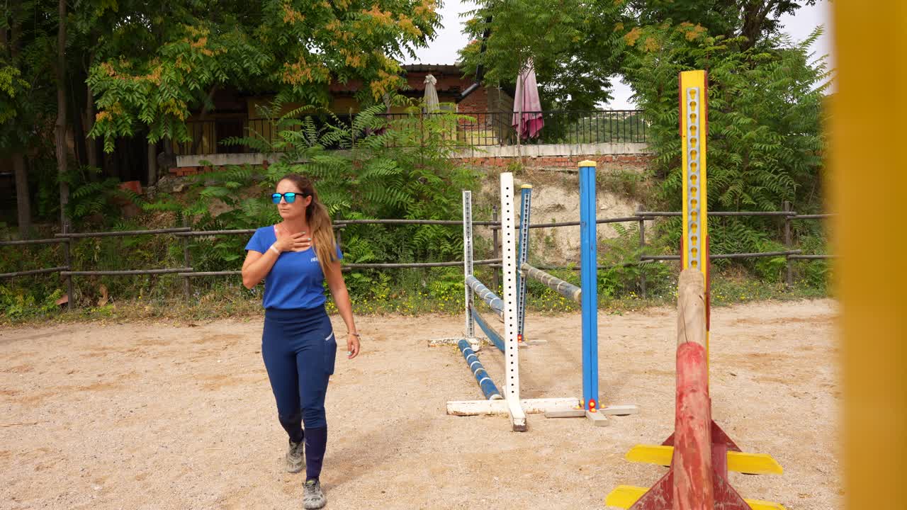 Riding trainer supervises riders while checking hurdle