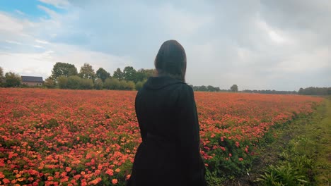 woman in dress walk in rain slomo trough orange marigold flower garden nursery