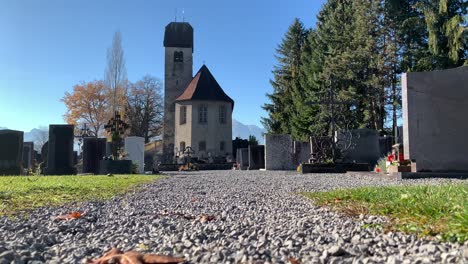 Una-Antigua-Iglesia-De-San-Miguel-Se-Encuentra-En-Medio-Del-Cementerio-Durante-El-Día-Con-Hojas-De-Otoño-Y-Cielo-Azul