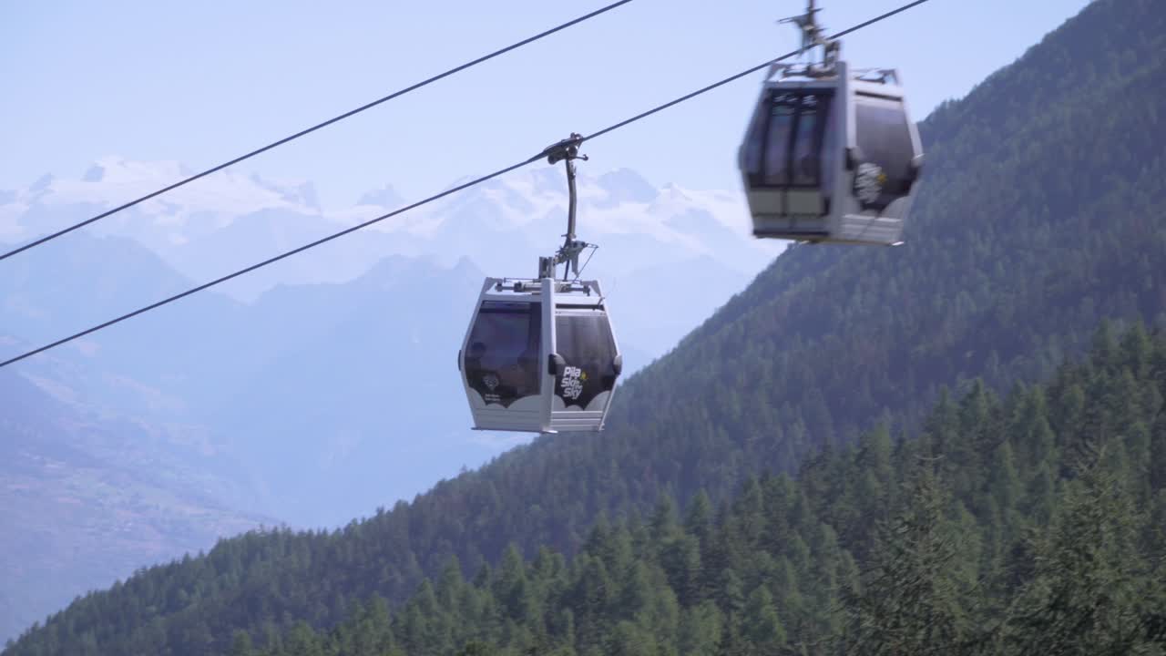 Cabina della funivia in salita sulle Alpi italiane, montagne sullo sfondo.