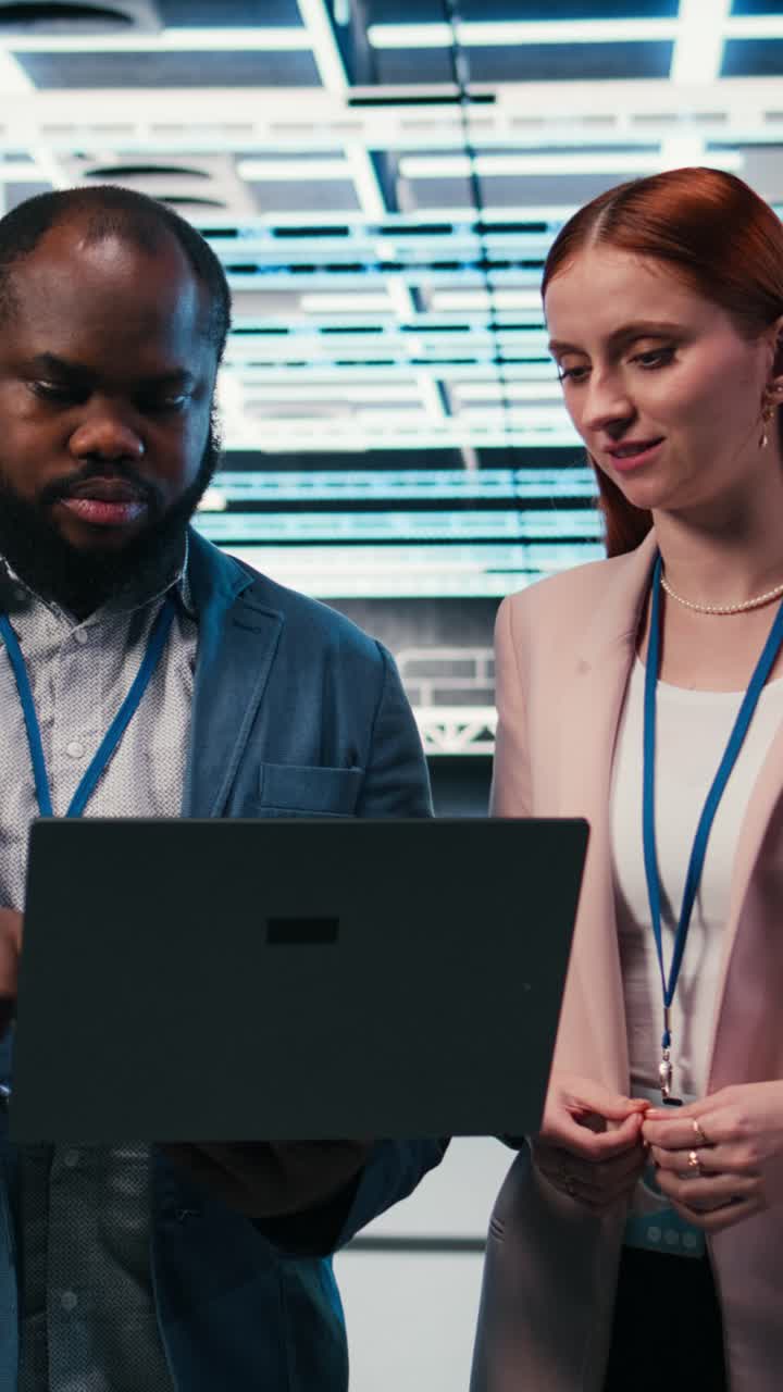 Vertical video Engineering team in server hub working together with laptop to do maintenance