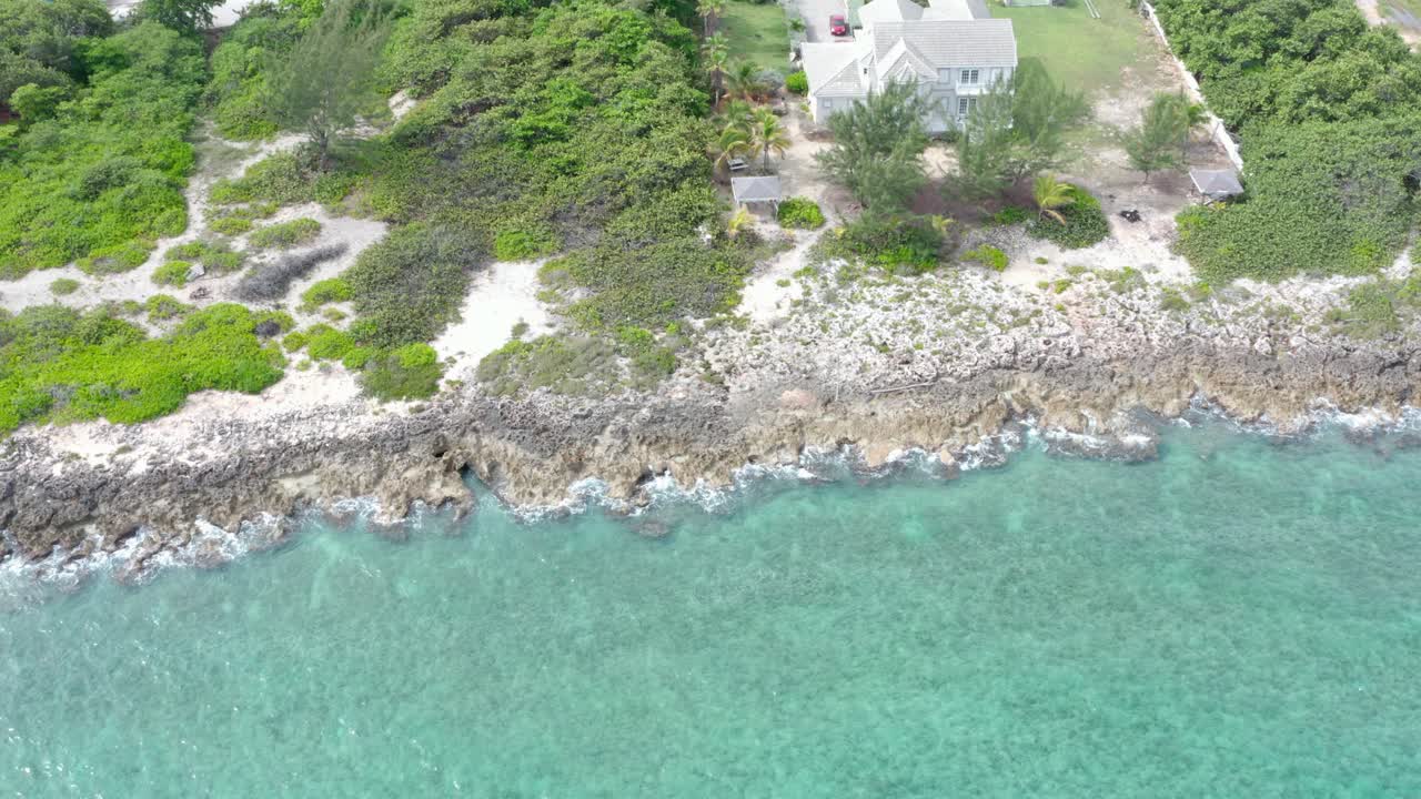 Areal shot of a beach moving downward then tracking along the coast.