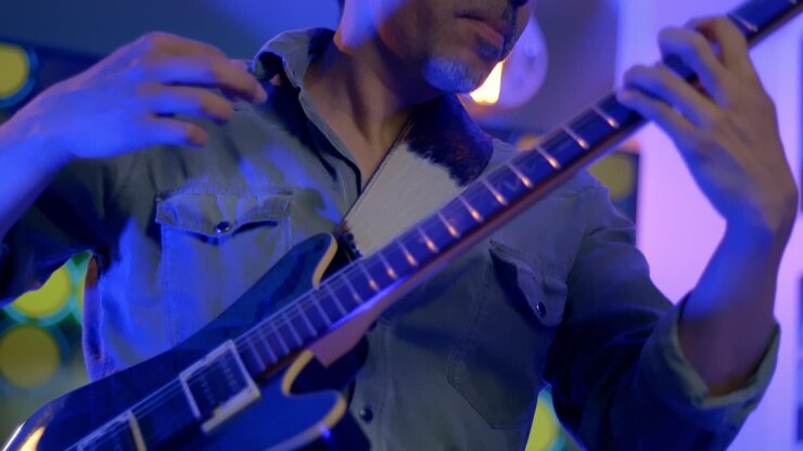 Primo piano di un musicista che suona la chitarra con gioia in un pub