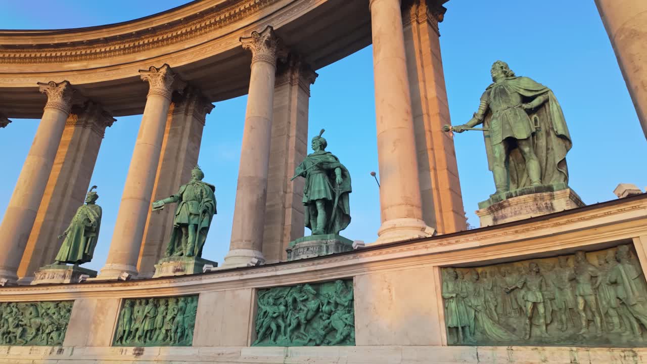 A cinematic pan left reveals the statues and colonnade at Heroes' Square in Budapest, Hungary, a UNESCO World Heritage site honoring historical Hungarian leaders and national heritage