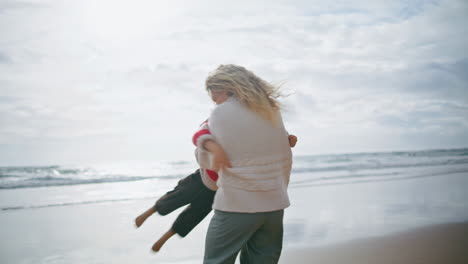 Niño-Juguetón-Corriendo-Madre-En-La-Orilla-Del-Océano.-Feliz-Padre-Mujer-Abrazo-Hilado-Niño