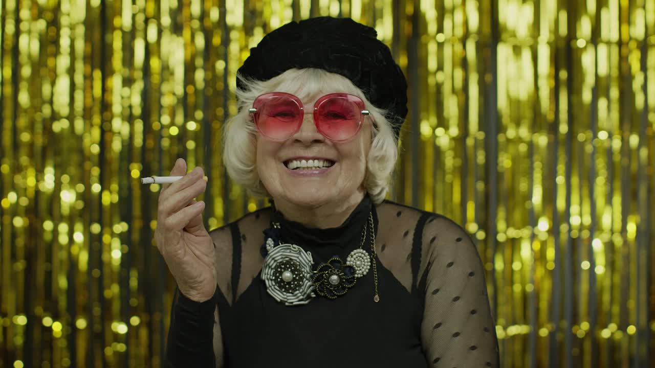 estilo anciana abuela madura en la moda ropa negra en gafas de sol posando, fumar cigarrillo