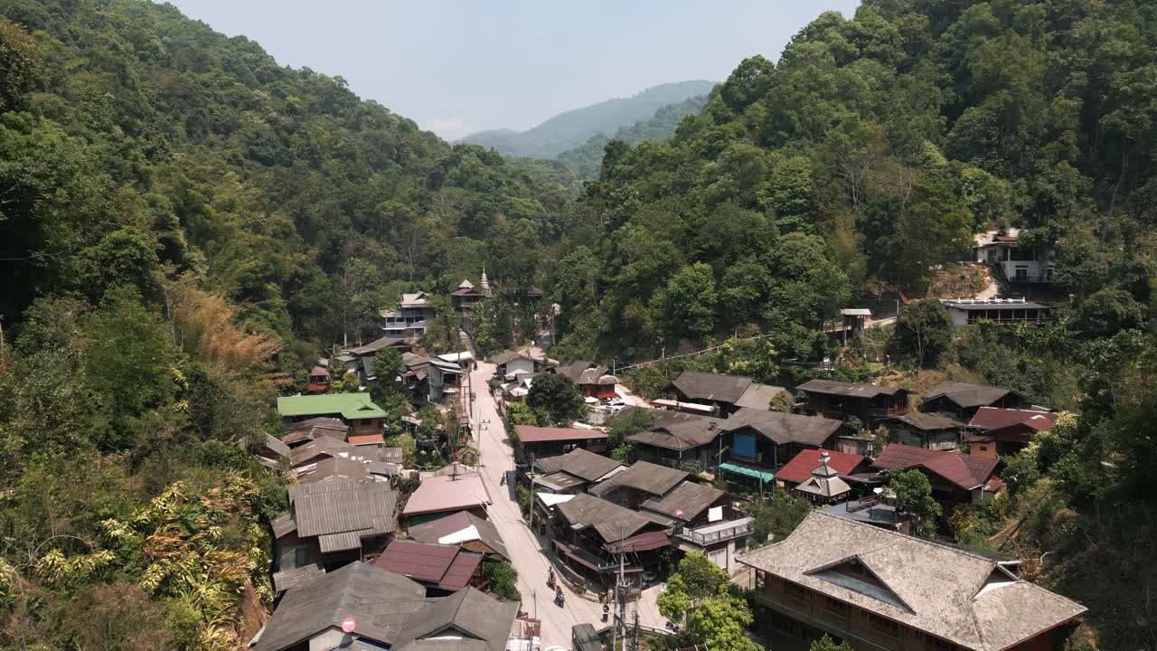 Vista aérea de drone da vila de Mae Kampong em Chiang Mai coberta por poluição atmosférica durante a estação de queimadas, destacando a poluição do ar em uma paisagem montanhosa cênica.