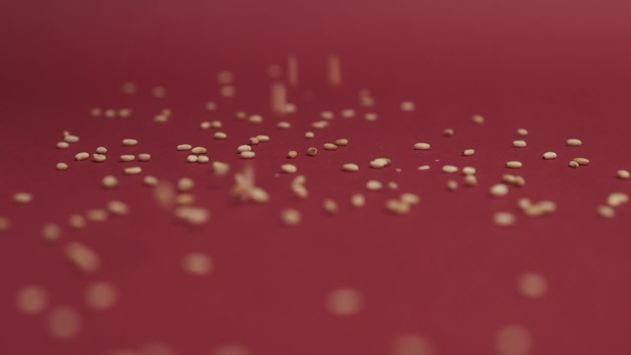 семена кунжута падают на красный фон