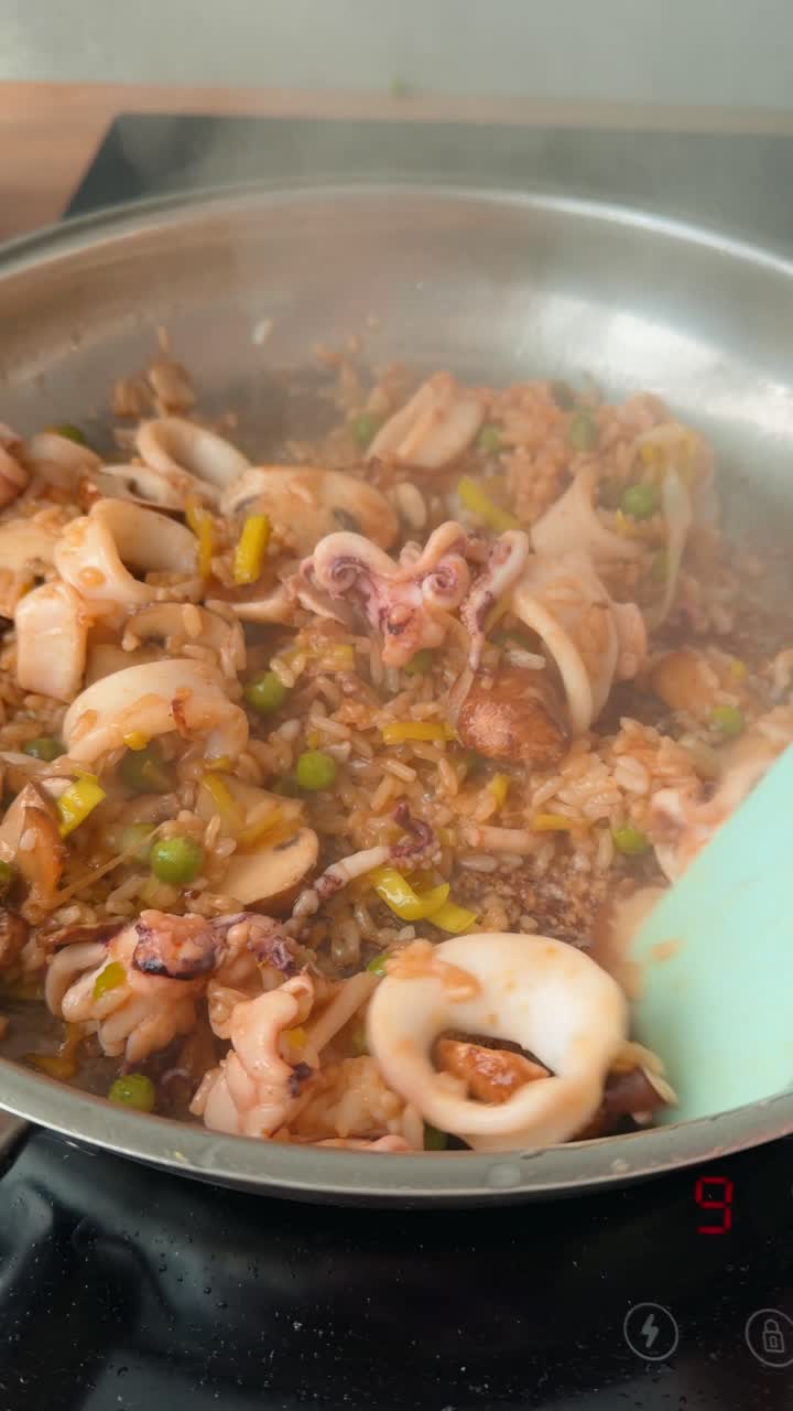 กำลังผัดปลาหมึก เห็ด และข้าวในกระทะร้อน