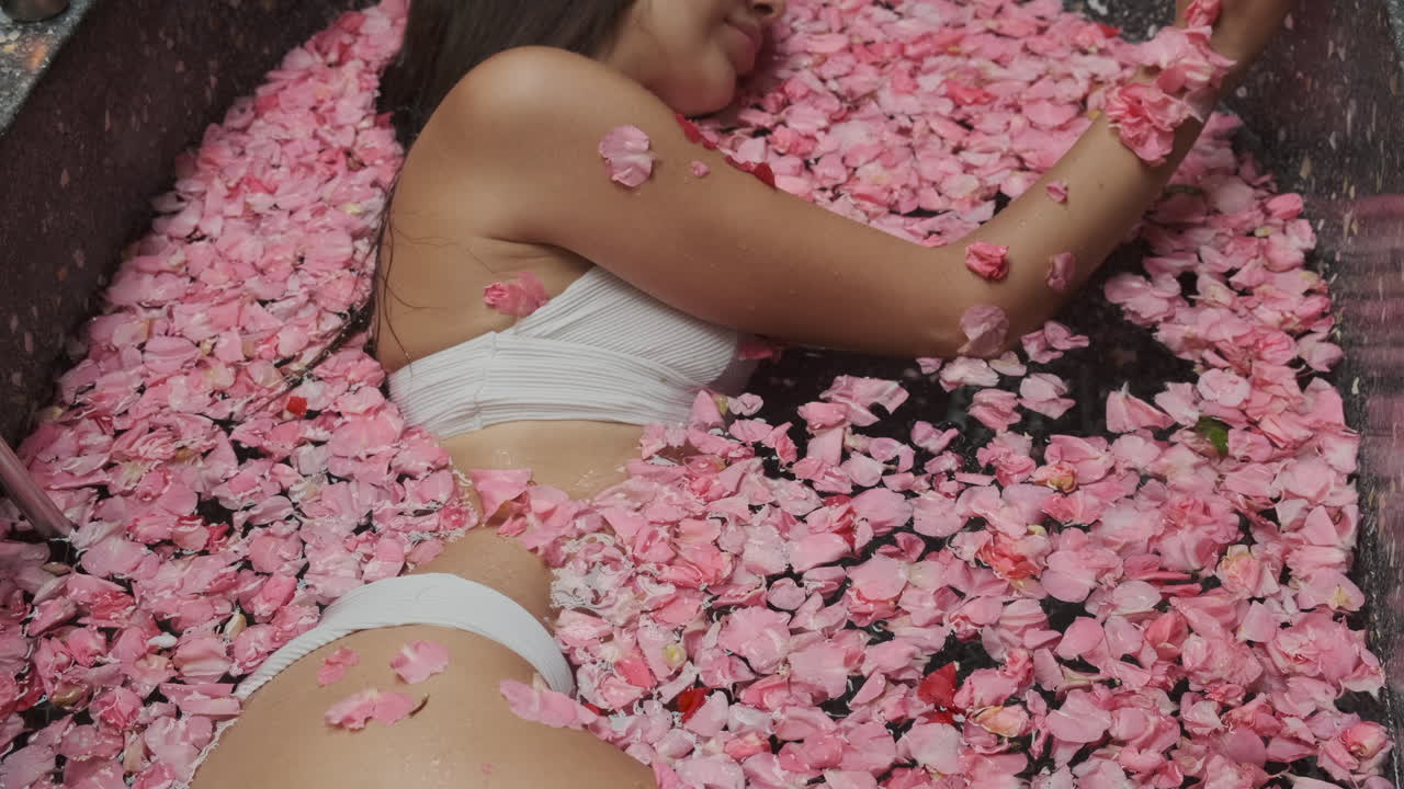 Donna in un bagno di petali di rosa