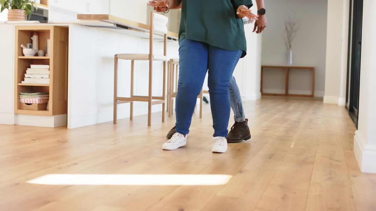 At setup male female dance partners practicing side to side stepping across floor by kitchen island