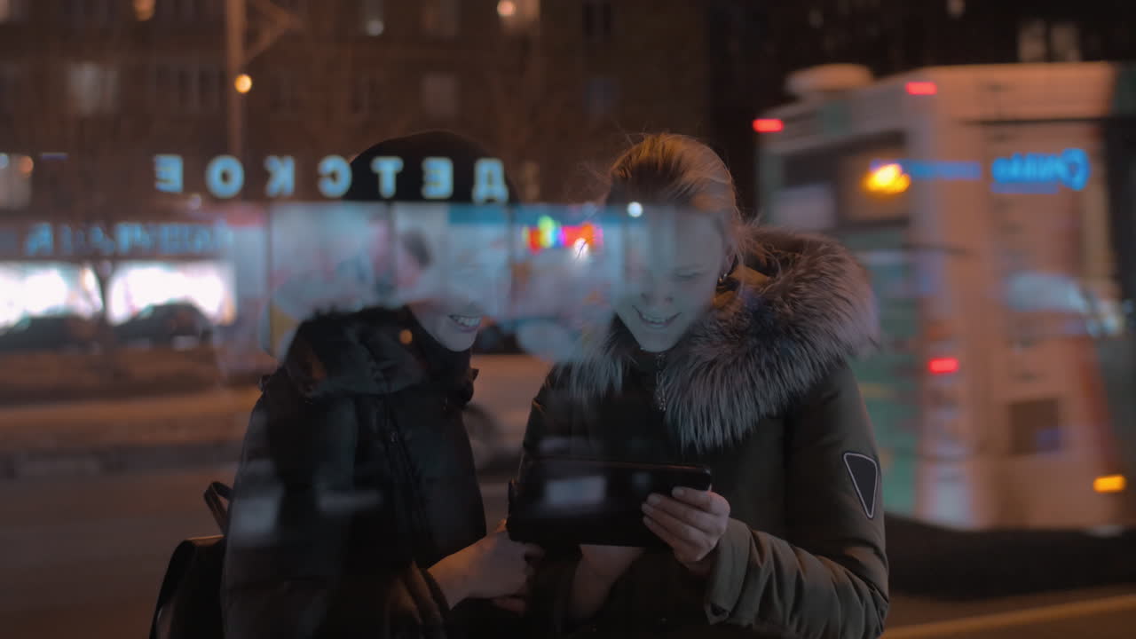 молодые женщины с сенсорной панелью в вечернем городе