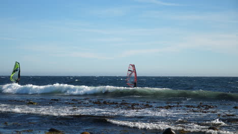 static shot of, two norwegian windsurfers sailing towards the horizon, at the north sea, in the atlantic ocean, on a sunny summer day, in lista, south norway