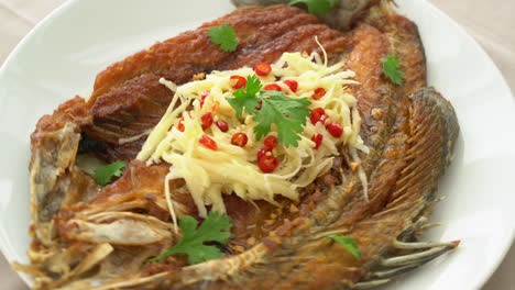 lubina frita con salsa de pescado y ensalada picante en el plato