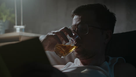 a sad man reads a book at night in his underwear