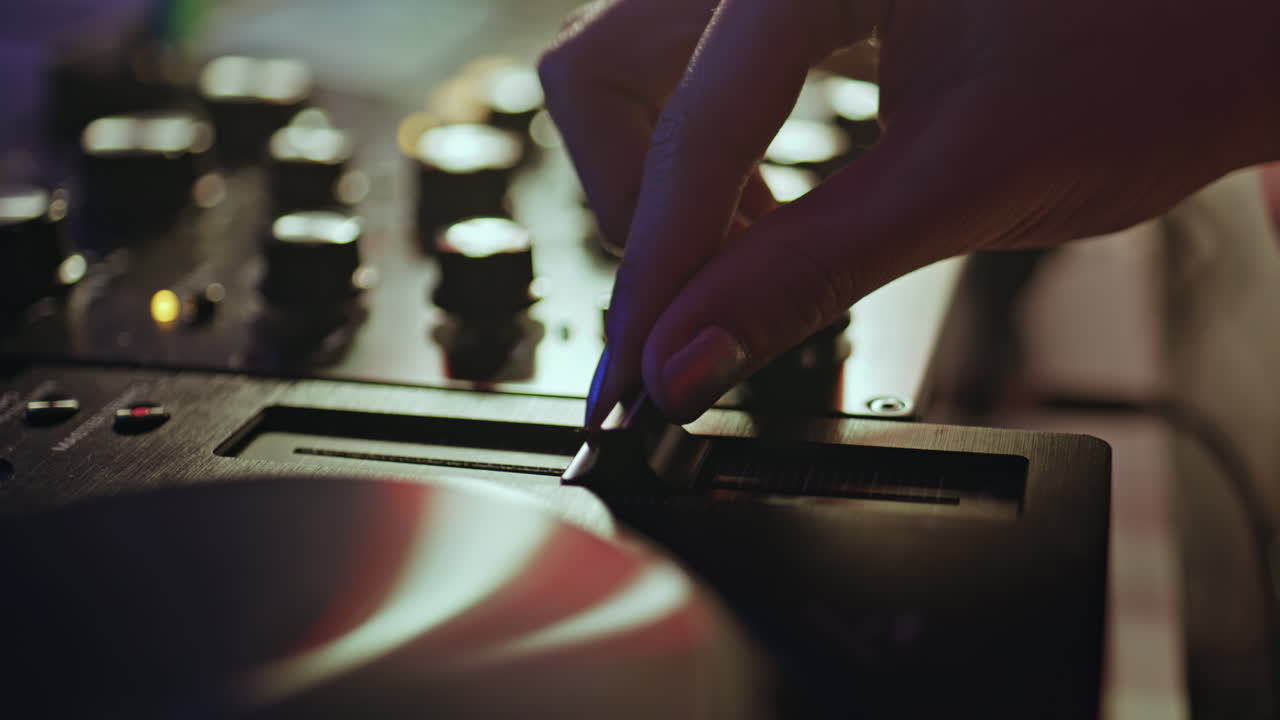 Hand adjusting slider DJ equipment in nightclub closeup. Unknown disc jockey