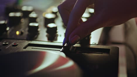 hand adjusting slider dj equipment in nightclub closeup. unknown disc jockey