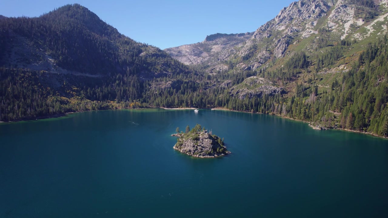 Una impresionante toma de dron de Emerald Bay en el lago Tahoe, con la icónica isla Fannette rodeada de aguas azules cristalinas, montañas alpinas y un denso bosque de hoja perenne.