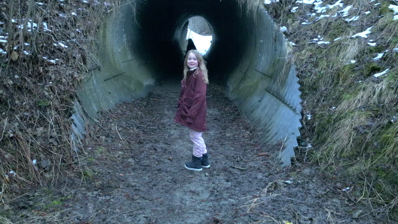 A little girl walking into a dark underground tunnel