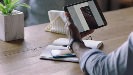 african american businessman using tablet computer in cafe browsing corporate documents enjoying drinking coffee reading email on mobile device screen browsing online close up hands