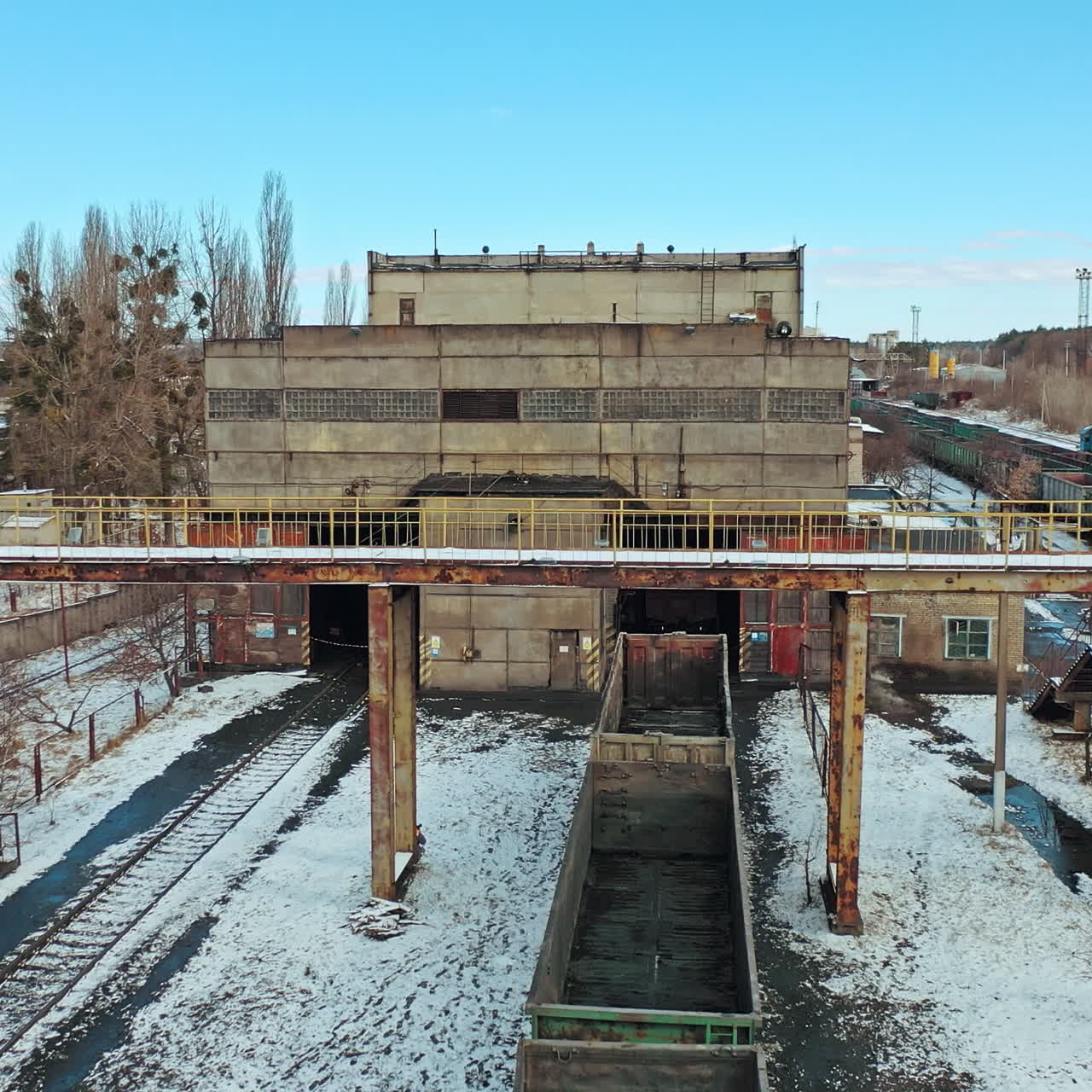 A row with containers on the railway line stand at the entrance to the tunnel on the background other rows in the terminal station in the winter season. Aerial view.