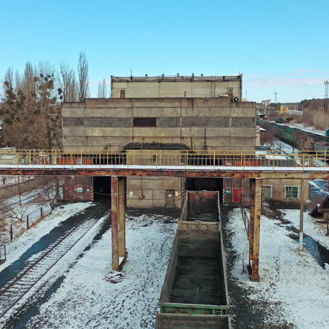 a row with containers on the railway line stand at the entrance to the tunnel on the background other rows in the terminal station in the winter season. aerial view.