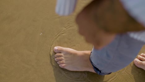 Top-view-closeup-shot-of-man-in-shirt-walking-at-seashore.