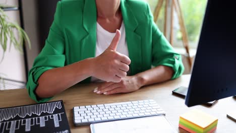 person giving thumbs up gesture at office desk