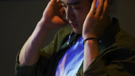 Male audio engineer listening to headphones while mixing sound