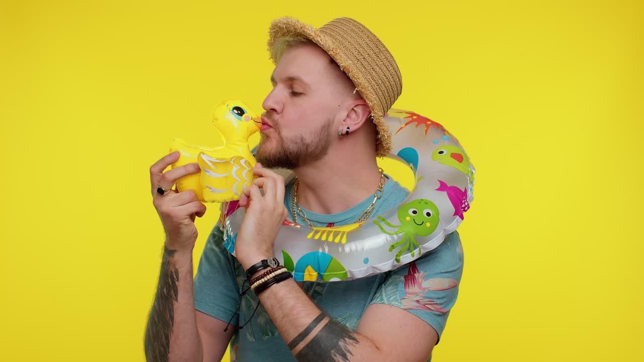 모자 를 입은 남자 가 미소 짓고 노란색 고무 오리 를 들고 있다