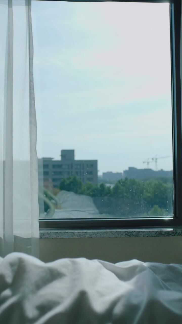 Vertical video: Showing bedroom window from bed edge, curtain drifting, blanket settling in breeze