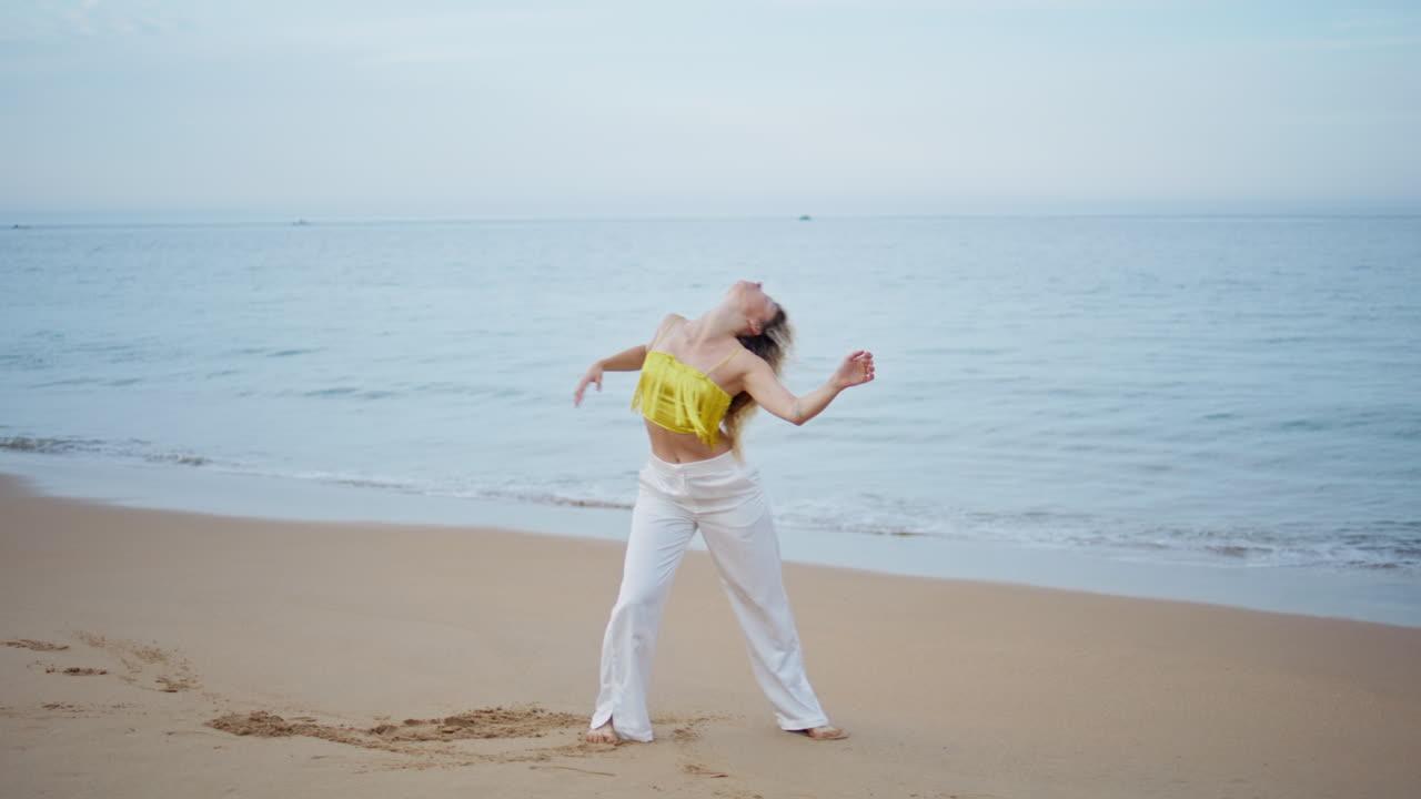 una mujer talentosa realizando una danza moderna en una playa de arena. bailarina de estilo libre.
