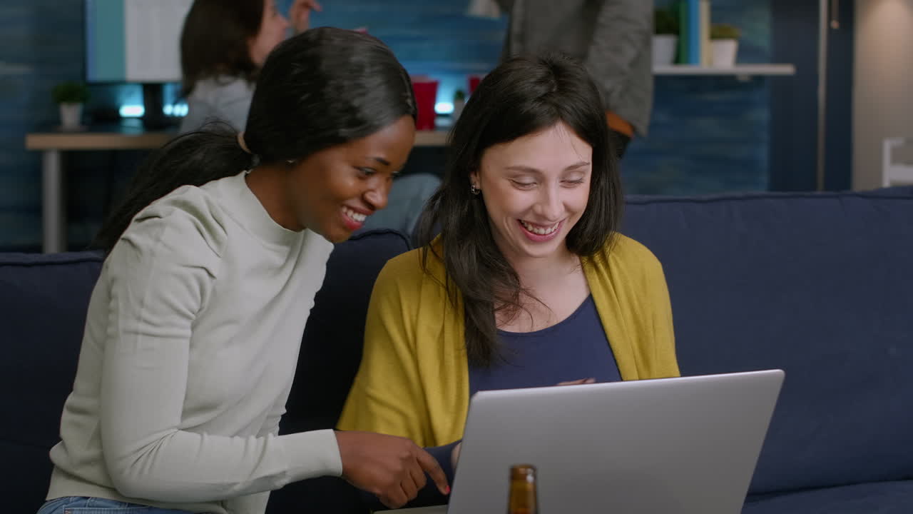 Mixed race women enjoying time spend together looking at movie on laptop