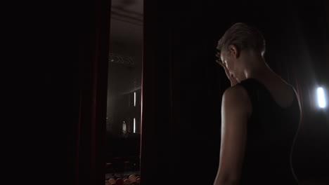 dancer standing behind a stage curtain waiting onstage and backstage fueled and prima ballet takes the stage for the beginning of the performance.