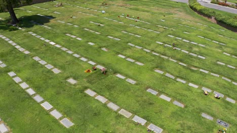 Absteigende-Und-Nach-Oben-Neigende-Luftaufnahme-Einer-Grabwiese-Mit-Reihen-Von-Grabsteinen,-Die-Mit-Blumen-Geschmückt-Sind,-In-Einer-Kalifornischen-Leichenhalle