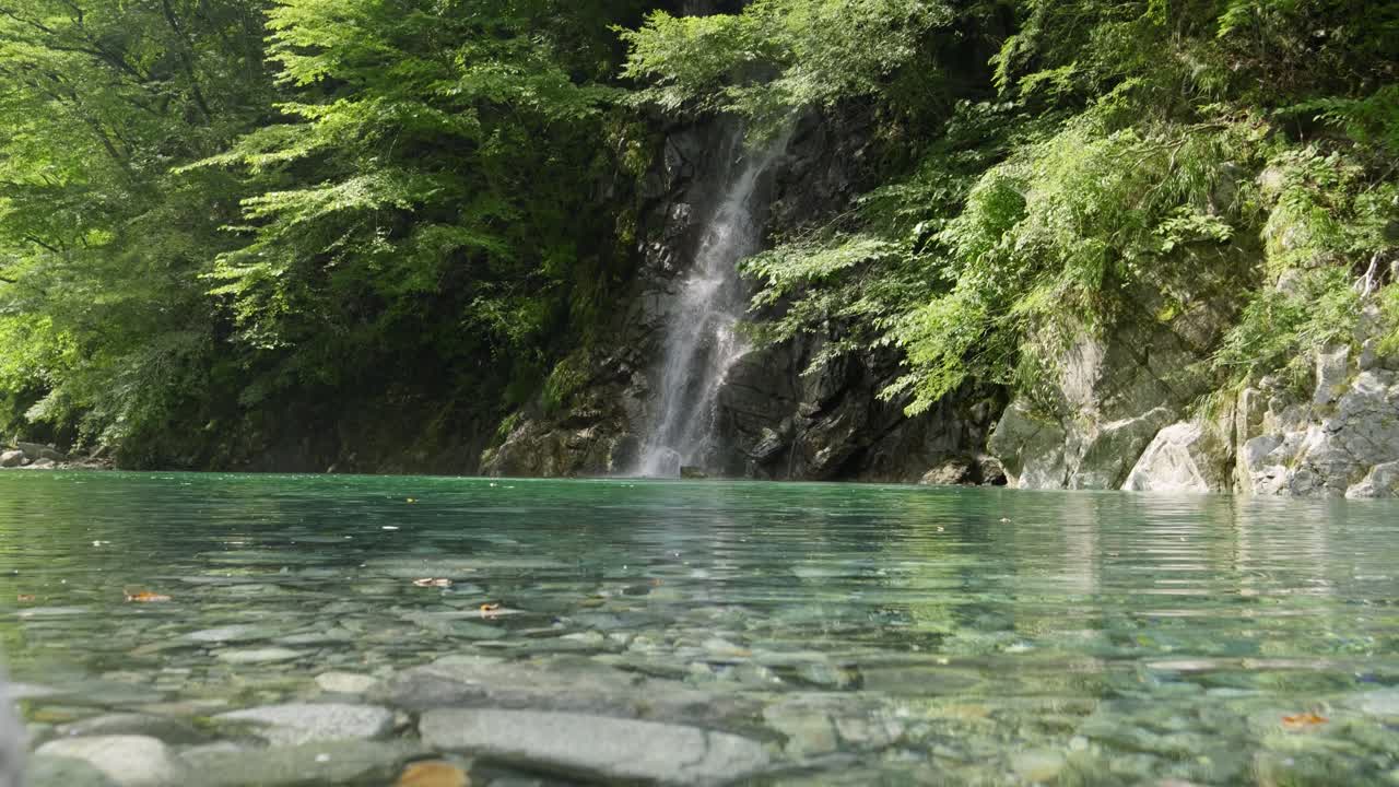 Stunning low angle slider shot over crystal clear water in Yushin Valley in Japan