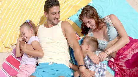 Happy-caucasian-family-lying-on-towels-at-beach-and-playing