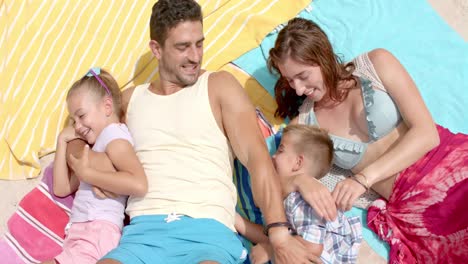 happy caucasian family lying on towels at beach and playing