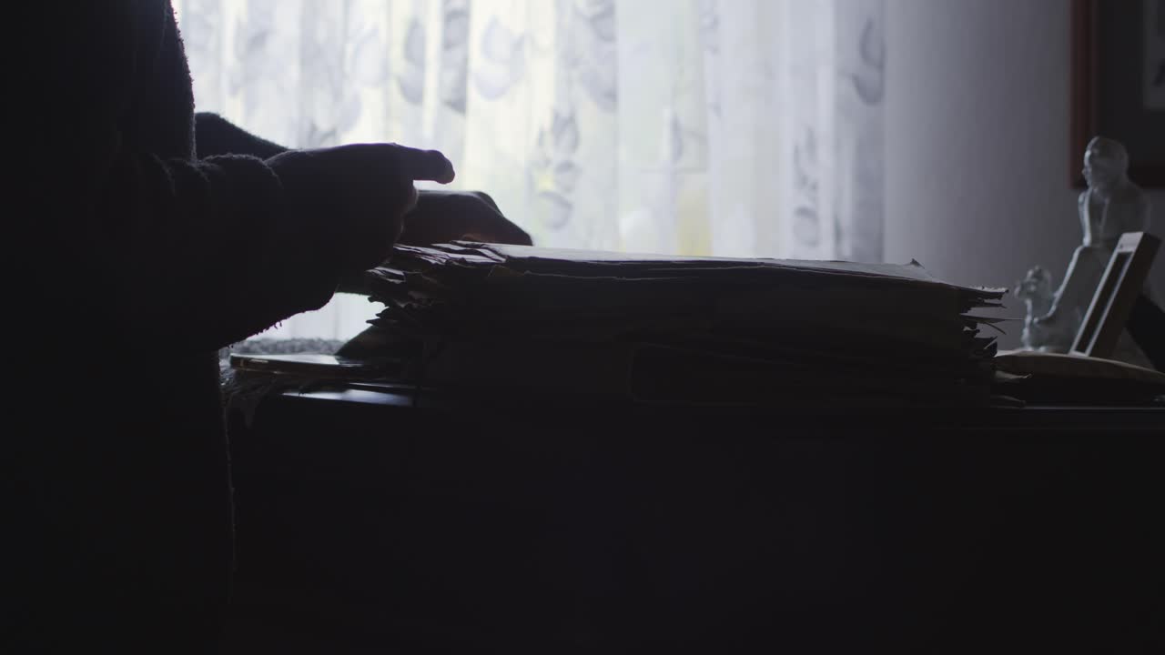 Back lit Silhouetted Figure searches personal Documents in dark office