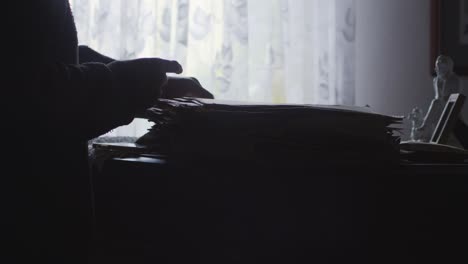 back lit silhouetted figure searches personal documents in dark office