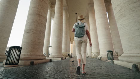 woman walking through colonnade in st. peter's square, vatican city
