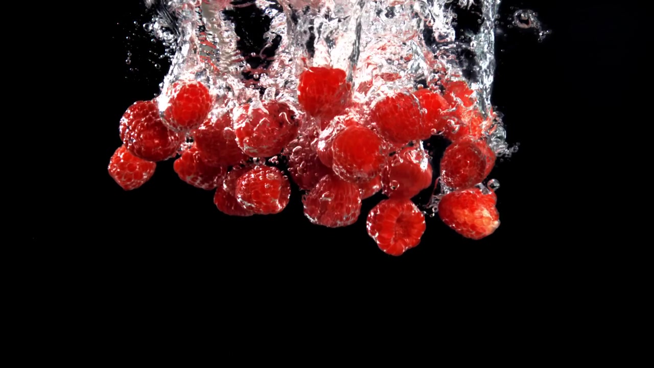 Red Raspberries Falling and Splashing into Water in Slow Motion