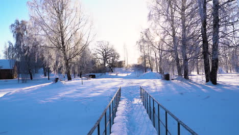 small bridge covered in snow leading to countryside farmstead, tilt up view