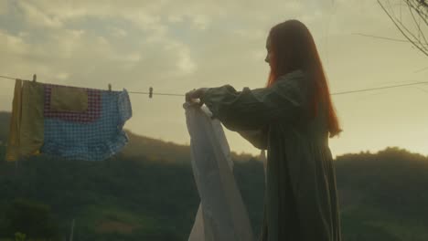 woman hanging laundry at sunset