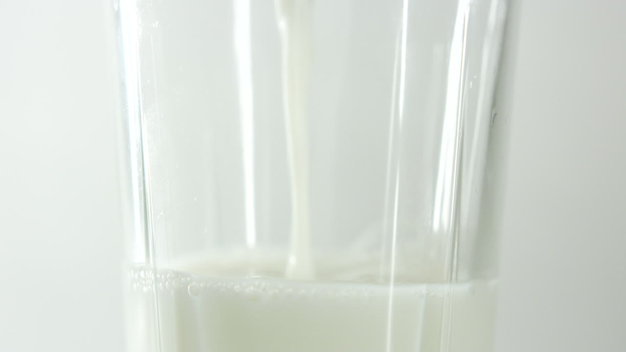 cámara lenta cerca de la sección central de un vaso que se llena con leche