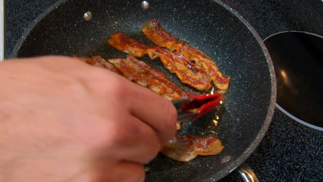 집에 있는 가스레인지 위에서 베이컨 뒤집기